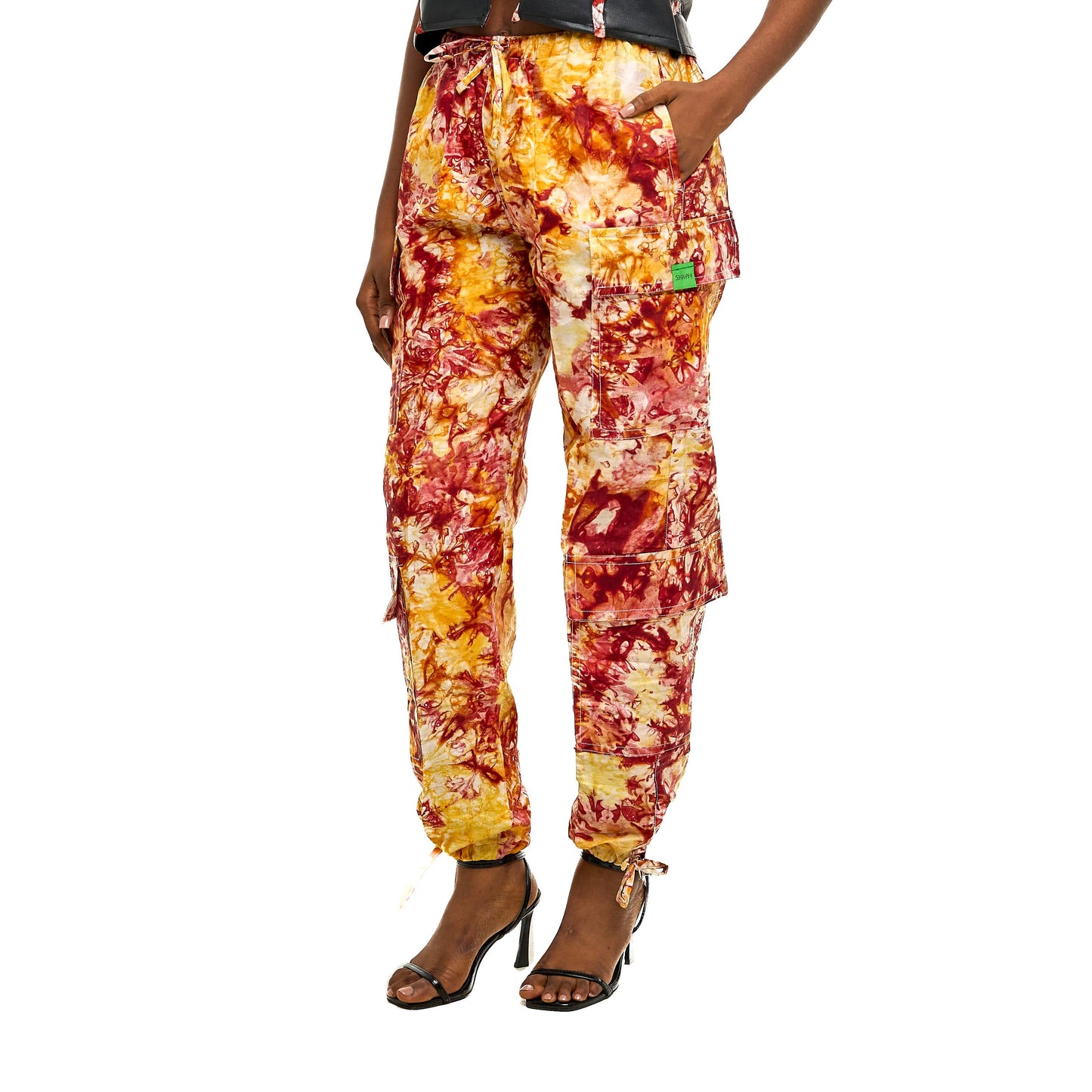 Woman wearing a black sleeveless top and colorful pants on a white background