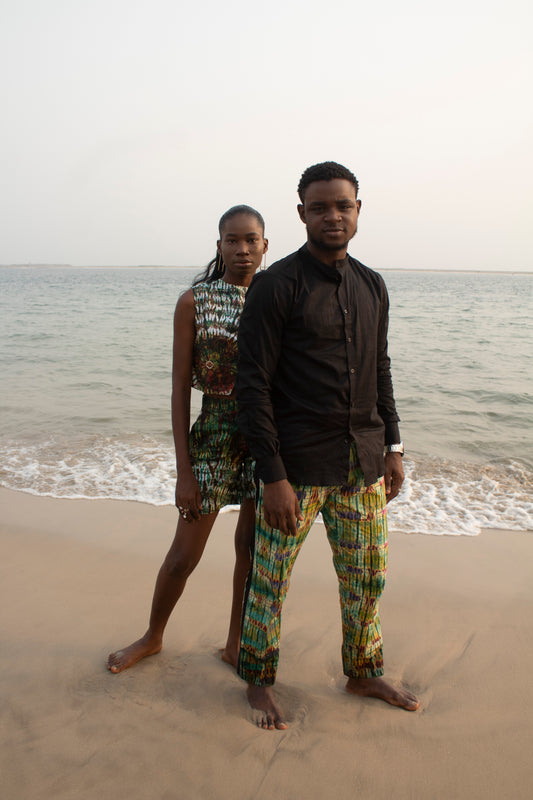 african couple on a beach wearing african adire print and a black shirt, barefoot