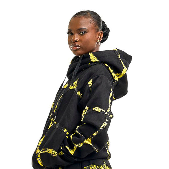 African woman wearing a black and yellow patterned hoodie on a white background