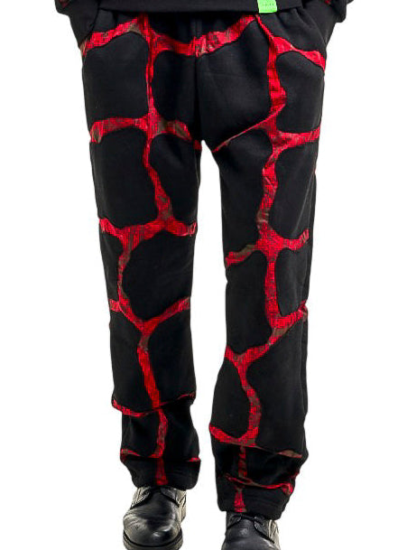 A man modeling a matching black hoodie and sweatpants set with a red cracked-glass pattern, standing against a solid white background.