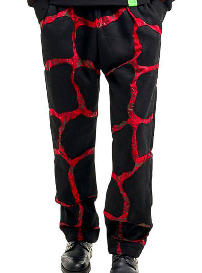 A man modeling a matching black hoodie and sweatpants set with a red cracked-glass pattern, standing against a solid white background.