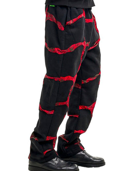 Person wearing a black and red patterned pants on a white background
