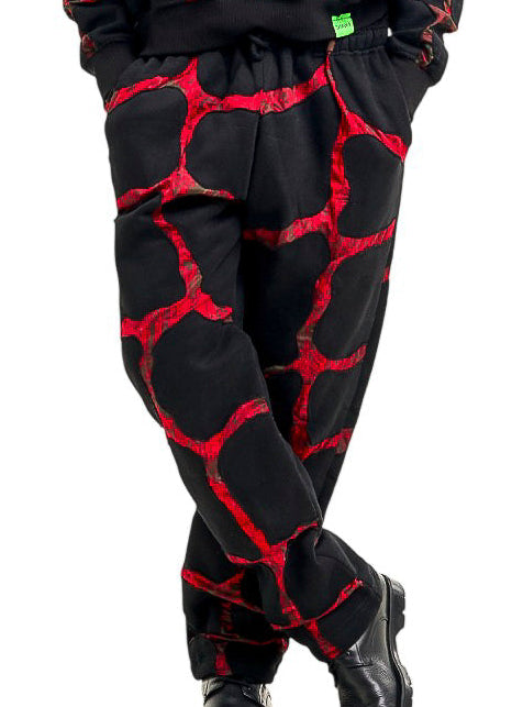 A man modeling a matching black and red patterned sweatpants set against a solid white background.