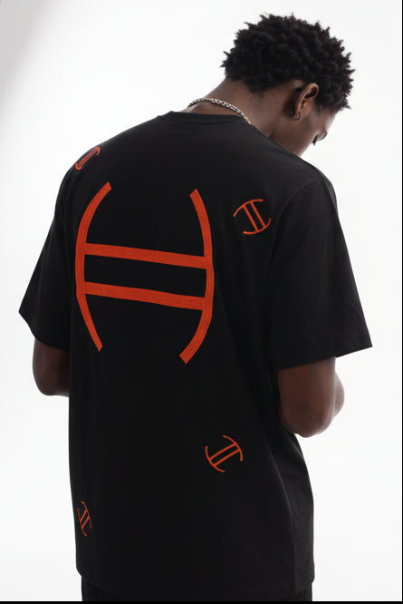 Person wearing a black t-shirt with orange symbols 